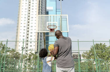 Vater und Sohn spielen Basketball an einem sonnigen Tag - IKF01241
