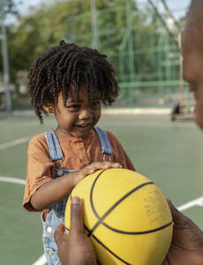 Vater gibt Basketball an spielenden Sohn auf Sportplatz - IKF01251
