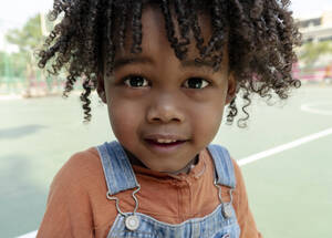 Lächelnder Junge mit lockigem Haar auf dem Basketballplatz - IKF01260