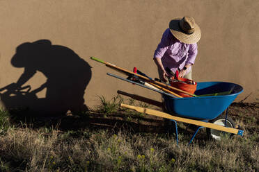 Senior woman with gardening equipment in desert garden - TETF02253