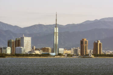 Japan, Präfektur Fukuoka, Fukuoka-Stadt, Wolkenkratzer an der Küste mit Bergen im Hintergrund - THAF03254