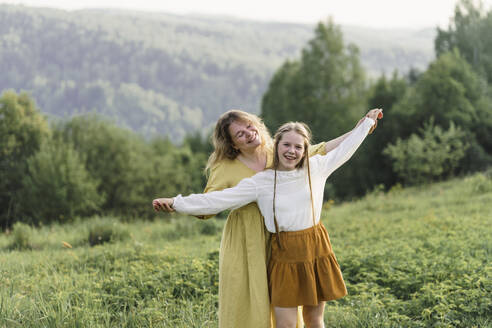 Happy mother and daughter spending leisure time in meadow - VBUF00391