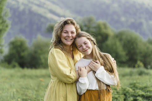 Happy mother and daughter embracing in meadow - VBUF00392