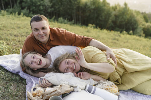 Happy family having fun and lying on blanket in meadow - VBUF00394