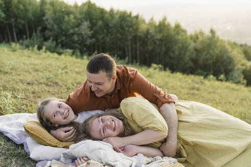 Smiling family having fun lying on blanket in meadow - VBUF00395