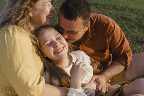 Smiling parents with daughter having fun on grass - VBUF00404