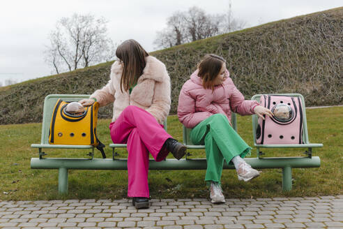 Zwei junge Frauen sitzen im Park neben Katzen in Tiertransportern - EHAF00100
