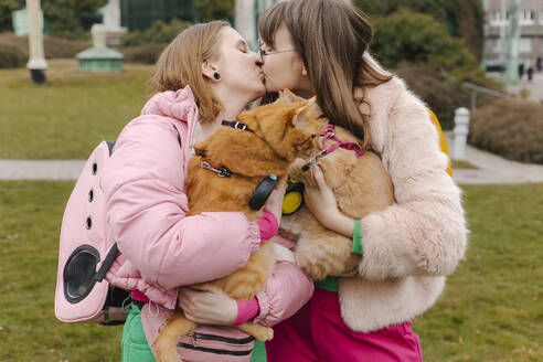 Lesbisches Paar trägt Katzen und küsst sich im Park - EHAF00106