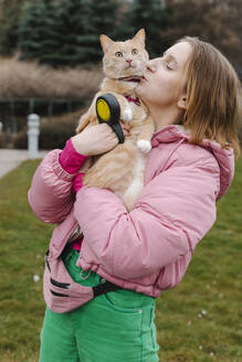 Junge Frau trägt und küsst Katze im Park - EHAF00110