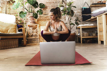 Schwangere Frau macht Yoga mit Laptop auf Matte zu Hause - PCLF00743