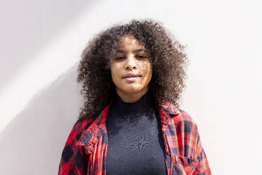 Smiling woman with curly hair in front of wall - WPEF07698