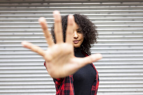 Woman showing stop gesture in front of shutter - WPEF07715