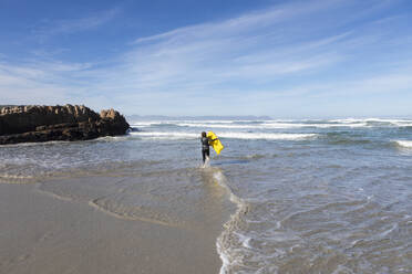 South Africa, Hermanus, Boy (10-11) entering Atlantic Ocean with body board in Kammabaai Beach - TETF02285