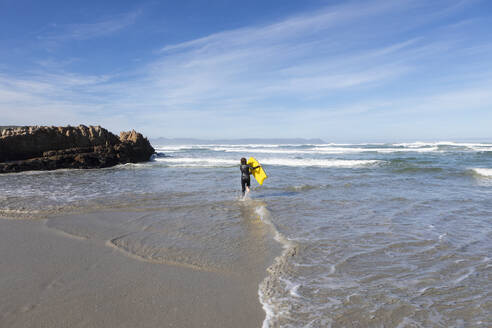 Südafrika, Hermanus, Junge (10-11), der am Strand von Kammabaai mit einem Bodyboard in den Atlantischen Ozean eintaucht - TETF02285
