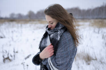 Portrait of freezing woman standing in snowy meadow - TETF02286