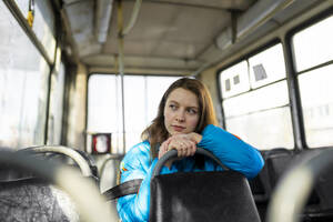 Porträt einer Frau, die in der Straßenbahn sitzend durch das Fenster schaut - TETF02287