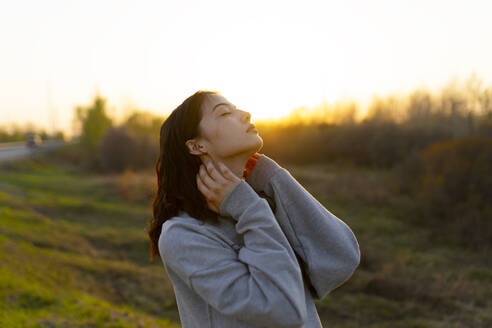 Portrait of thoughtful woman with closed eyes in meadow at sunset - TETF02290