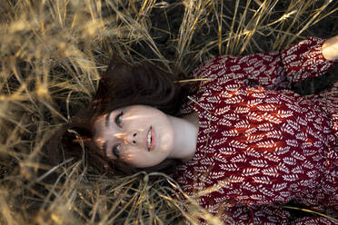 Directly above view of woman lying on cereal plants in field - TETF02302