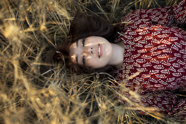 Directly above view of woman lying on cereal plants in field - TETF02303
