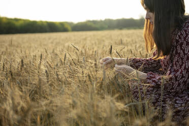 Side view of woman touching cereal plant in field - TETF02304