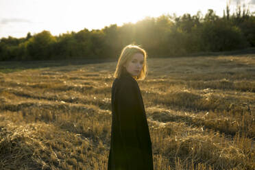 Portrait of young woman standing in field at sunset - TETF02308