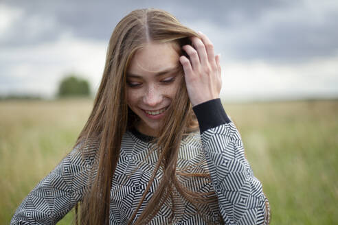 Smiling young woman standing in field - TETF02313