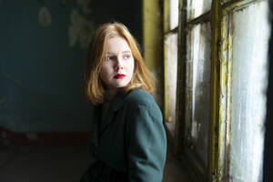 Teenage girl (16-17) wearing red lipstick, looking though window - TETF02325