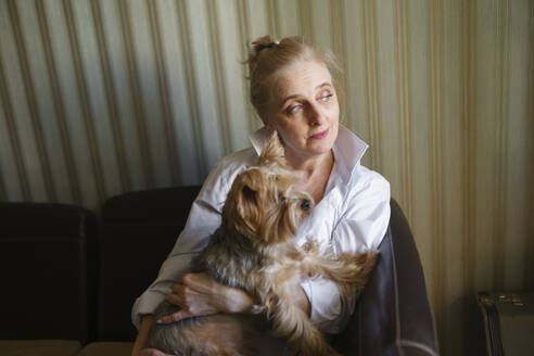 Frau sitzt auf dem Sofa und hält einen Yorkshire Terrier - TETF02336