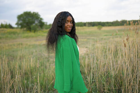 Brunette woman wearing green blouse and standing in field - TETF02342