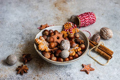 Von oben auf einen Teller mit einem Haufen Kastanien und leckeren Weihnachtsplätzchen, die auf dem Tisch neben einer Spule mit rotem Faden liegen - ADSF47868