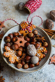 Top view of plate of heap of chestnuts with tasty Christmas cookies placed on table near spool of red thread - ADSF47869