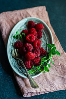 From above plate with ripe blackberries and mint leaf placed on a dark concrete table - ADSF47885