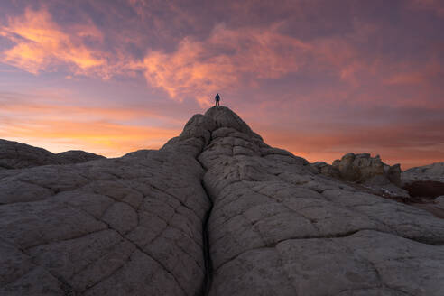 Silhouette eines nicht erkennbaren Forschers, der auf einem Felsen steht, gegen einen bewölkten Himmel bei Sonnenuntergang während einer Reise in bergigem Gelände - ADSF47925