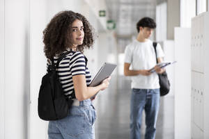 Lächelnde Studentin mit Laptop im Korridor - LMCF00612