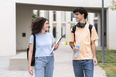 Lächelnde Studenten, die vor einem Gebäude auf dem Campus stehen - LMCF00652