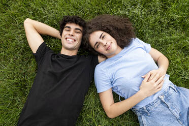 Happy man and woman lying on grass - LMCF00665