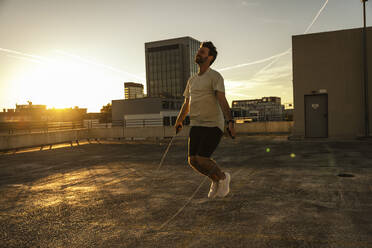 Man jumping over rope at terrace - UUF30582