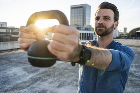 Mann trainiert mit Kettlebell auf der Terrasse - UUF30595