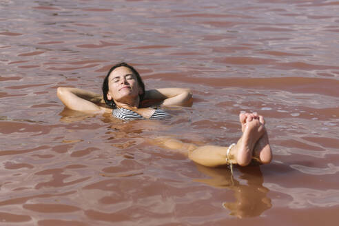 Smiling woman floating on lake - SIF00915