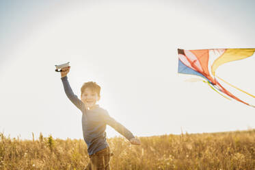 Smiling boy flying kite in field - ANAF02150