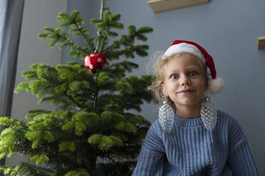 Blondes Mädchen macht Gesicht und trägt Weihnachtsschmuck in den Ohren zu Hause - SVKF01622
