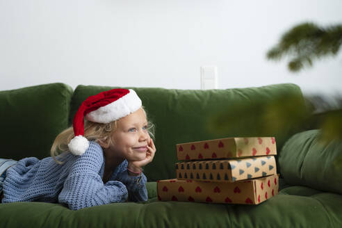 Lächelndes Mädchen in der Nähe von Weihnachtsgeschenken zu Hause - SVKF01635