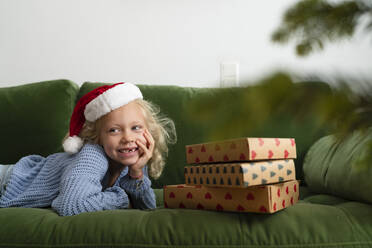 Glückliches Mädchen, das bei den Weihnachtsgeschenken zu Hause liegt - SVKF01636