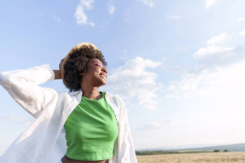 Carefree young woman wearing hat in field - AAZF01076