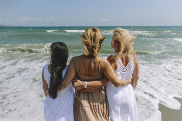 Friends looking at sea standing with arms around on shore - SIF00925