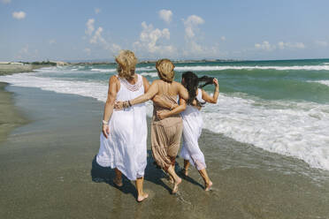 Women walking with arms around walking together near sea at beach - SIF00931