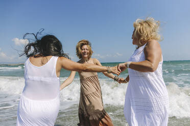 Happy women enjoying together near wavy sea at beach - SIF00939