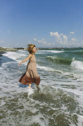 Carefree woman with arms outstretched enjoying near shore at beach - SIF00941