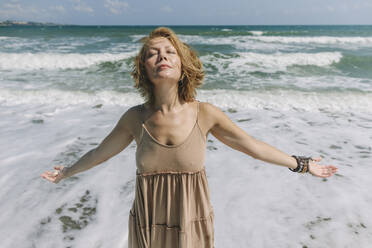 Woman with eyes closed standing near sea at beach - SIF00948