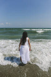 Frau schaut am Strand stehend aufs Meer - SIF00952